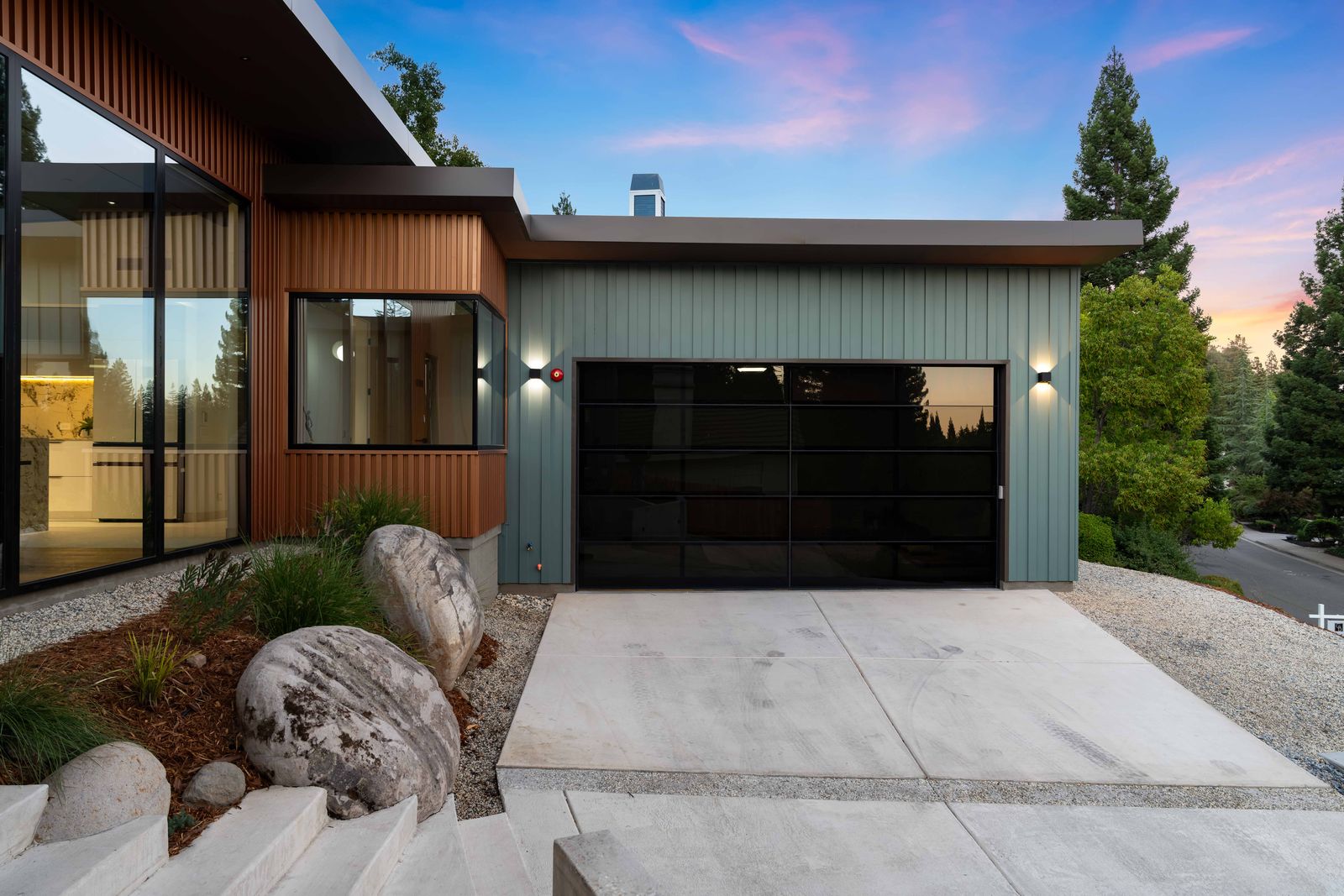 Garage exterior with glass door, copper siding and boulder landscaping